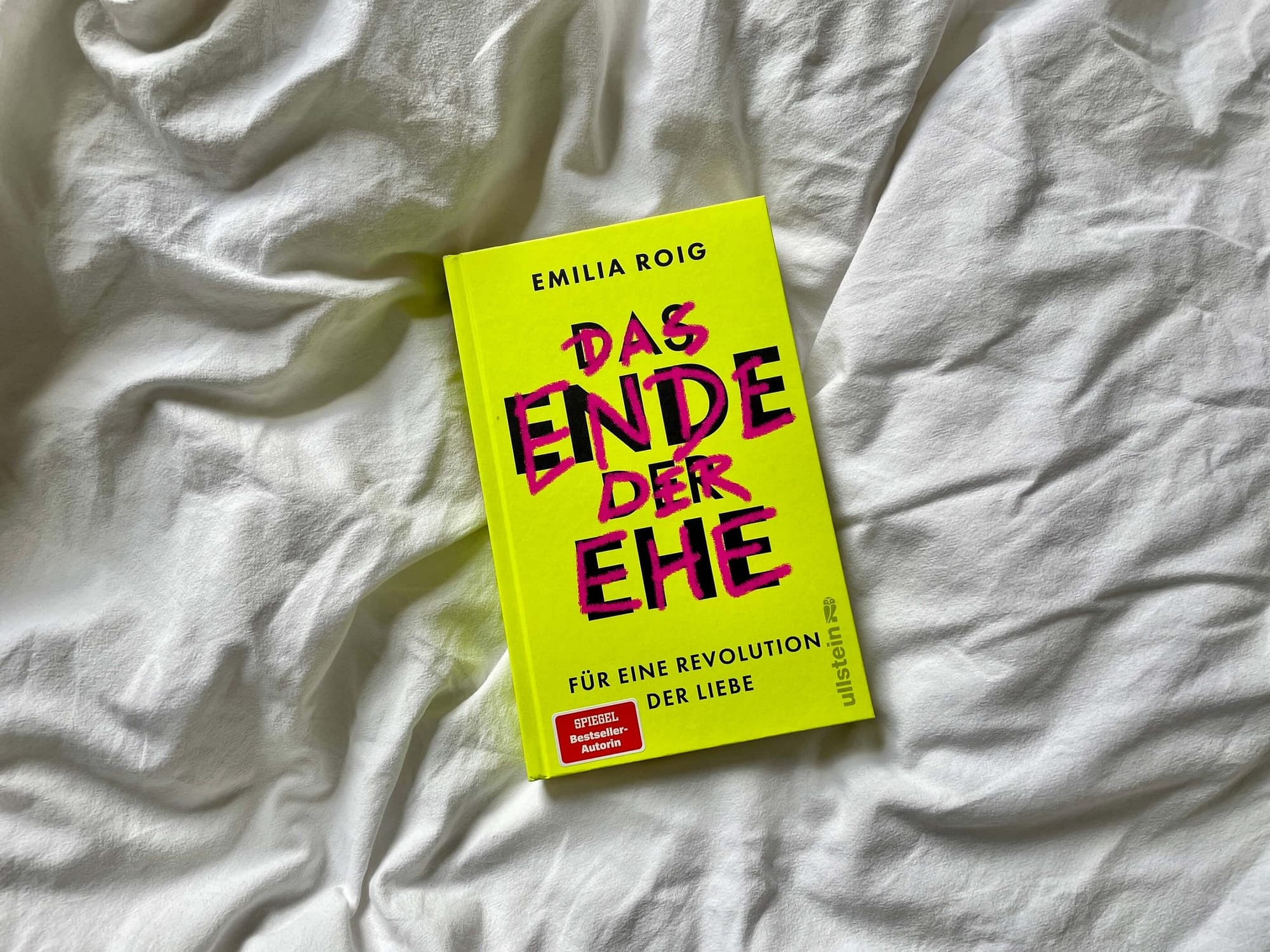 Das Buch "Das Ende der Ehe" von Emilia Roig liegt auf einem weißen Bettlaken
