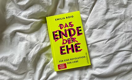 Das Buch "Das Ende der Ehe" von Emilia Roig liegt auf einem weißen Bettlaken
