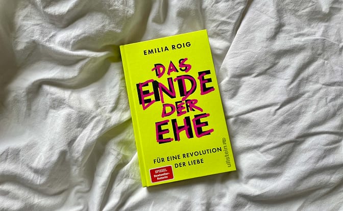 Das Buch "Das Ende der Ehe" von Emilia Roig liegt auf einem weißen Bettlaken